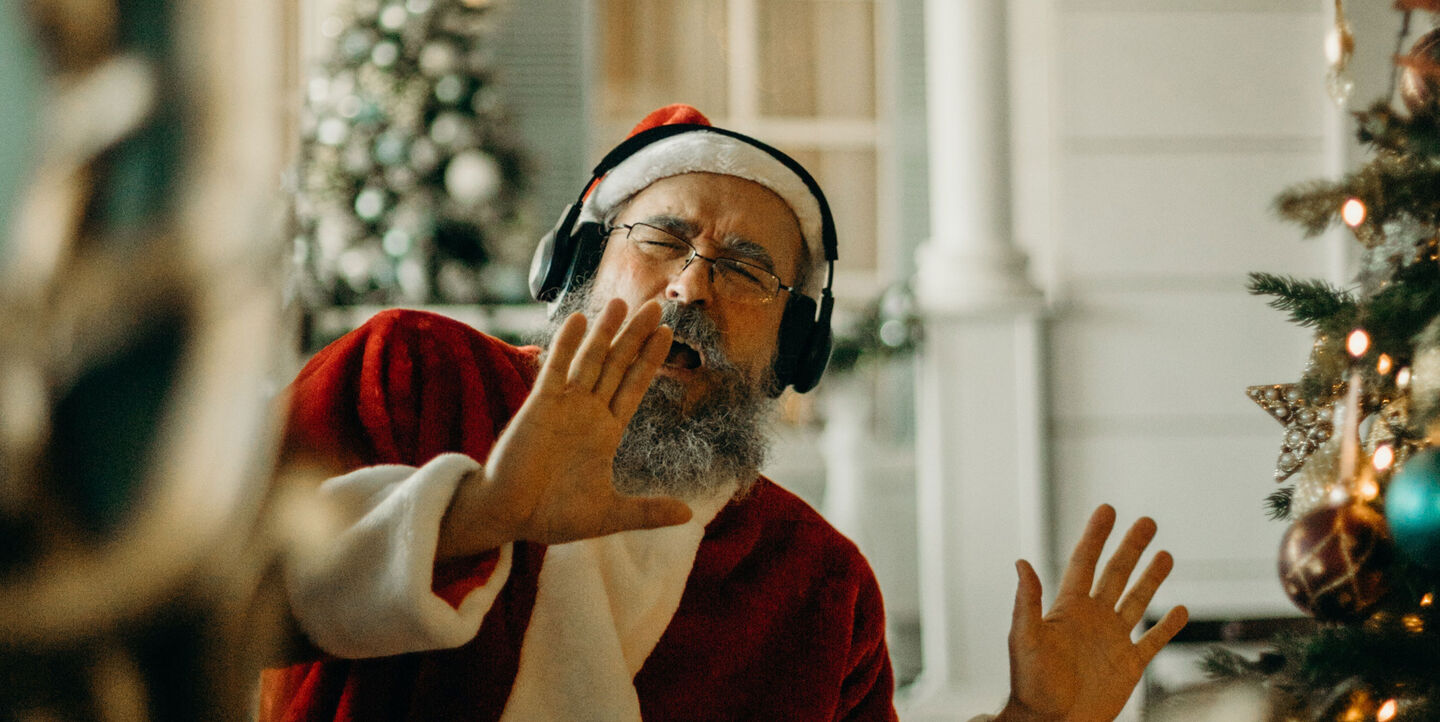 Singender und tanzender Weihnachtsmann mit Kopfhörern. 
